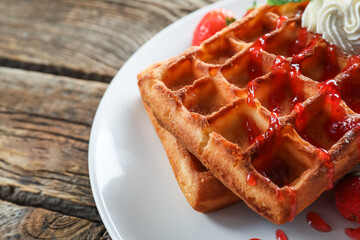 Plate of tasty Belgian Waffles with strawberry on wooden background, closeup