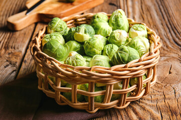 Wicker basket with raw Brussels cabbage on wooden background