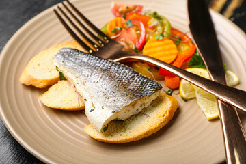 Plate of delicious sea bass fish with vegetables on table, closeup