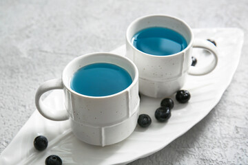 Cups of organic blue tea and blueberry on light background, closeup