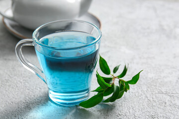 Glass cup of organic blue tea on light background, closeup