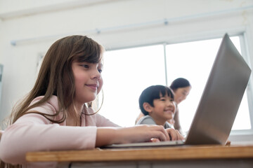 Happy Smiling little Cute girl using laptop while studying in classroom at international school.