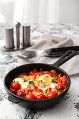 Frying pan with tasty Shakshouka on table