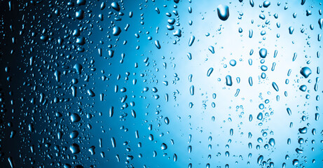 Naklejka na ściany i meble Water drops with foam on glass on a blue background.