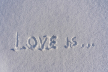 Text love is on a white fresh snow in winter, close up