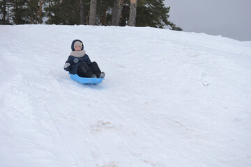 The girl slides down the snow slide and smiles