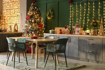 Dining table and tree with glowing lights in kitchen decorated for Christmas