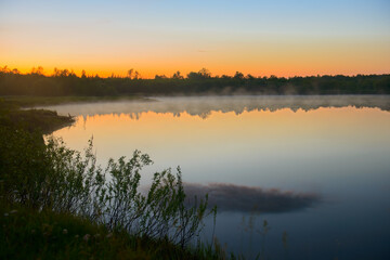 Fototapeta na wymiar Fog over the lake on a beautiful summer evening