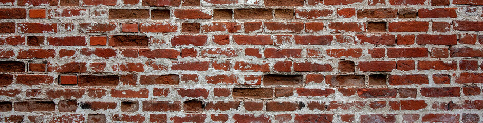 Fragment of old brickwork, wide plan. A wall of red brick. Potholes and defects in a brick wall, side view.
