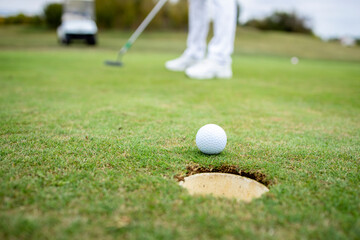 Professional unrecognizable golfer putting ball into the hole on golf course.