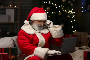 Santa Claus using laptop at home on Christmas eve