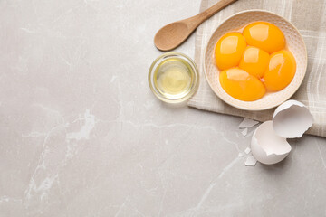 Flat lay composition with raw egg yolks and whites on light grey marble table, space for text