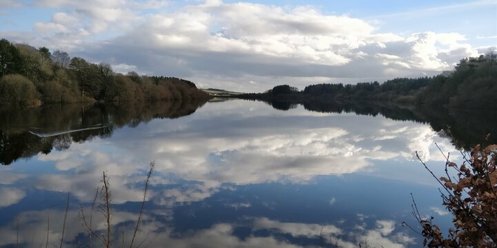 Looking over Entwistle Reservoir, Bolton, England reflective water and sky photo with tree lined shores.