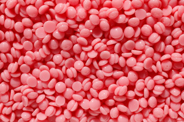 Beautiful pink depilation hot wax granules. Background texture of pink depilatory wax. Epilation, depilation, unwanted hair removal. Top view.