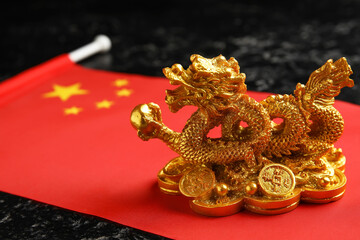 Figurine of dragon and Chinese flag on dark background