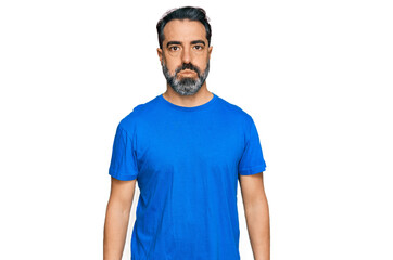 Middle aged man with beard wearing casual blue t shirt puffing cheeks with funny face. mouth inflated with air, crazy expression.