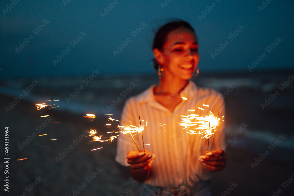 Wall mural Female  hand holding burning Christmas sparkle on nature. Holidays, vacation, relax, travel and lifestyle concept.