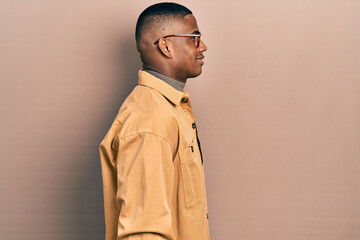 Young black man wearing casual clothes and glasses looking to side, relax profile pose with natural face with confident smile.