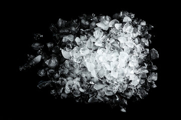 Heap of crushed ice on black table, top view