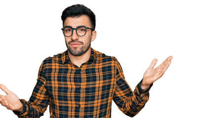 Hispanic man with beard wearing casual clothes and glasses clueless and confused expression with...