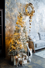 The Christmas tree in Christmas decorations stands on a minimalist background. Christmas and New Year's mood. Decorations for the holiday