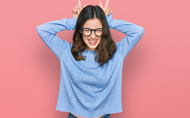 Young beautiful woman wearing casual clothes and glasses posing funny and crazy with fingers on head as bunny ears, smiling cheerful