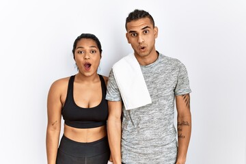Young latin couple wearing sportswear standing over isolated background afraid and shocked with surprise expression, fear and excited face.