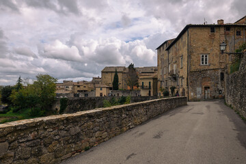 Fototapeta na wymiar ausblick von Volterra auf die toskansiche Landscahft mit Himmel und Wolken und Gebäuden im Vordergrund und Straße mit Mauer