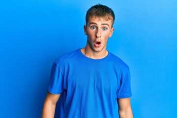 Fototapeta premium Young caucasian man wearing casual blue t shirt afraid and shocked with surprise and amazed expression, fear and excited face.