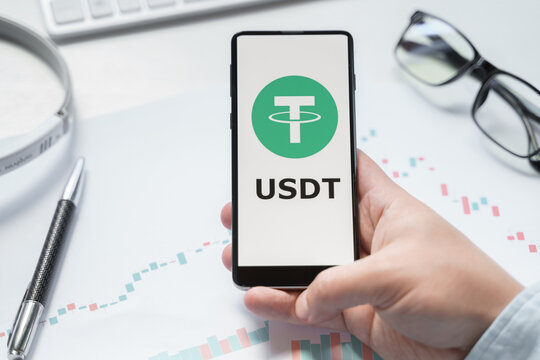 Russia Moscow 08.06.2021 Man holding logo of Tether USDT token in mobile phone. Cryptocurrency stablecoin. Cryptocurrency token USDT. Trading blockchain decentralized exchange DEX. Digital money