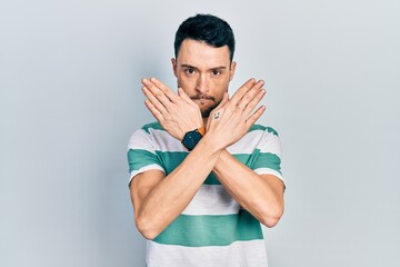 Young hispanic man wearing casual clothes rejection expression crossing arms doing negative sign, angry face