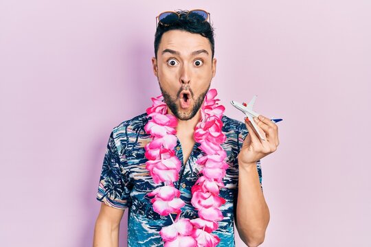 Young hispanic man wearing summer style holding airplane toy scared and amazed with open mouth for surprise, disbelief face
