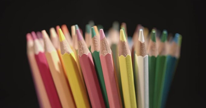 Rotating multicolored pencils or slow spinning pastel toned pencils. Many-colored cryons rotate or revolve in a circle around the central or vertical axis. 4K DCI resolution.