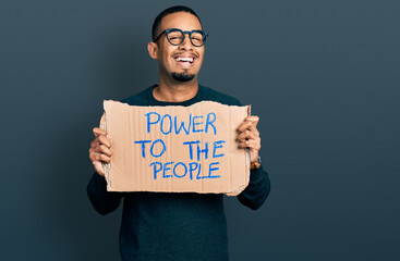 Young african american man holding power to the people banner celebrating crazy and amazed for success with open eyes screaming excited.