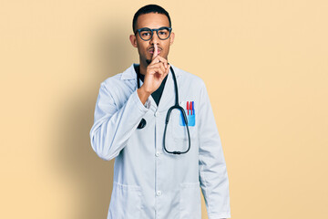 Young african american man wearing doctor uniform and stethoscope asking to be quiet with finger on lips. silence and secret concept.