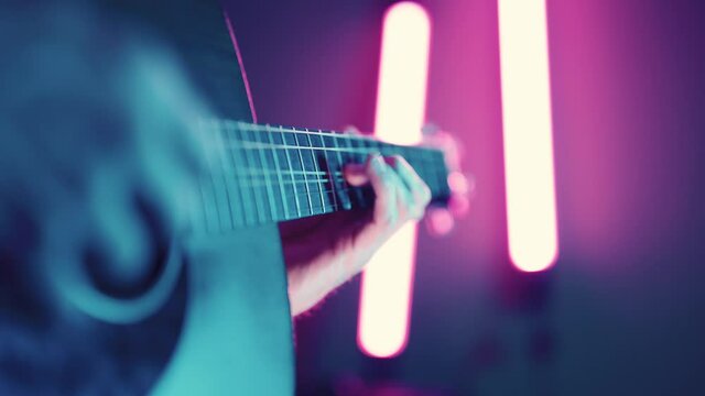 Musician playing acoustic dreadnought guitar with atmospheric purple LED lighting