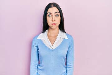 Beautiful woman with blue eyes standing over pink background puffing cheeks with funny face. mouth...