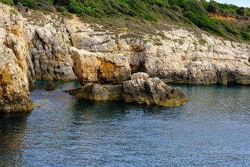 Fels vor den Klippen Istriens Kroatien im Meer mit gelb-braunen Felsenformationen.