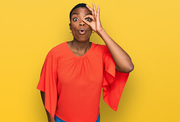 Young african american woman wearing casual clothes doing ok gesture shocked with surprised face, eye looking through fingers. unbelieving expression.