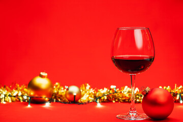 Glass of wine with christmas decoration on red background christmas drink concept