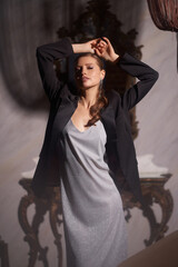 Elegant woman having fun at night party in luxury dark interior. Pretty stylish girl in silver shiny dress and black blazer