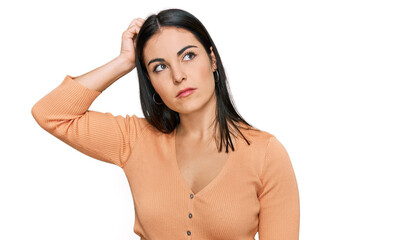 Young hispanic woman wearing casual clothes confuse and wondering about question. uncertain with...