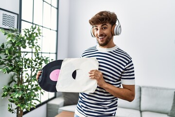 Young arab man smiling confident listening to music and holding vinyl disc at home
