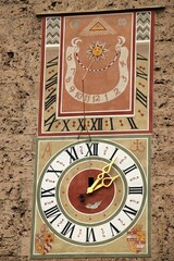 antique church tower wall Wessobrunn monastery with big clock with golden clock hands, Roman numerals black and white and above big sun dial