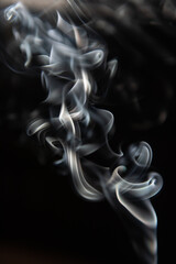 Formes abstraites, fumée d'encens sur fond noir.