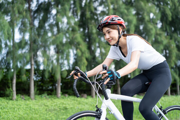 Asian young sport woman riding bicycle in the evening in public park.