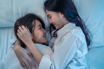 Asian beautiful lesbian couple lying down on bed and hugging each other. 