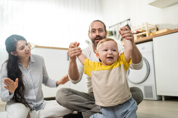 Caucasian happy baby boy child dancing with parents support in house. 
