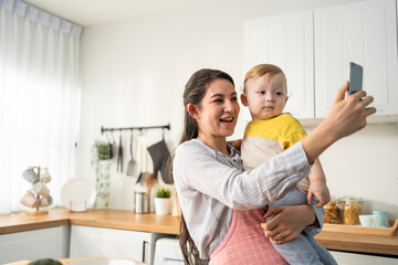 Caucasian mother holding little baby and video call online with family.