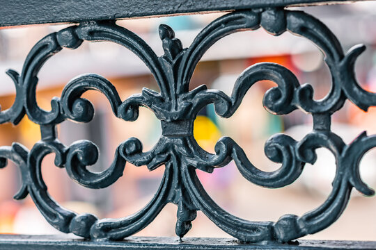 Close up of beautiful wrought iron fence in the French Quarter in New Orleans, Louisiana, with Bourbon Street blurred beyond.